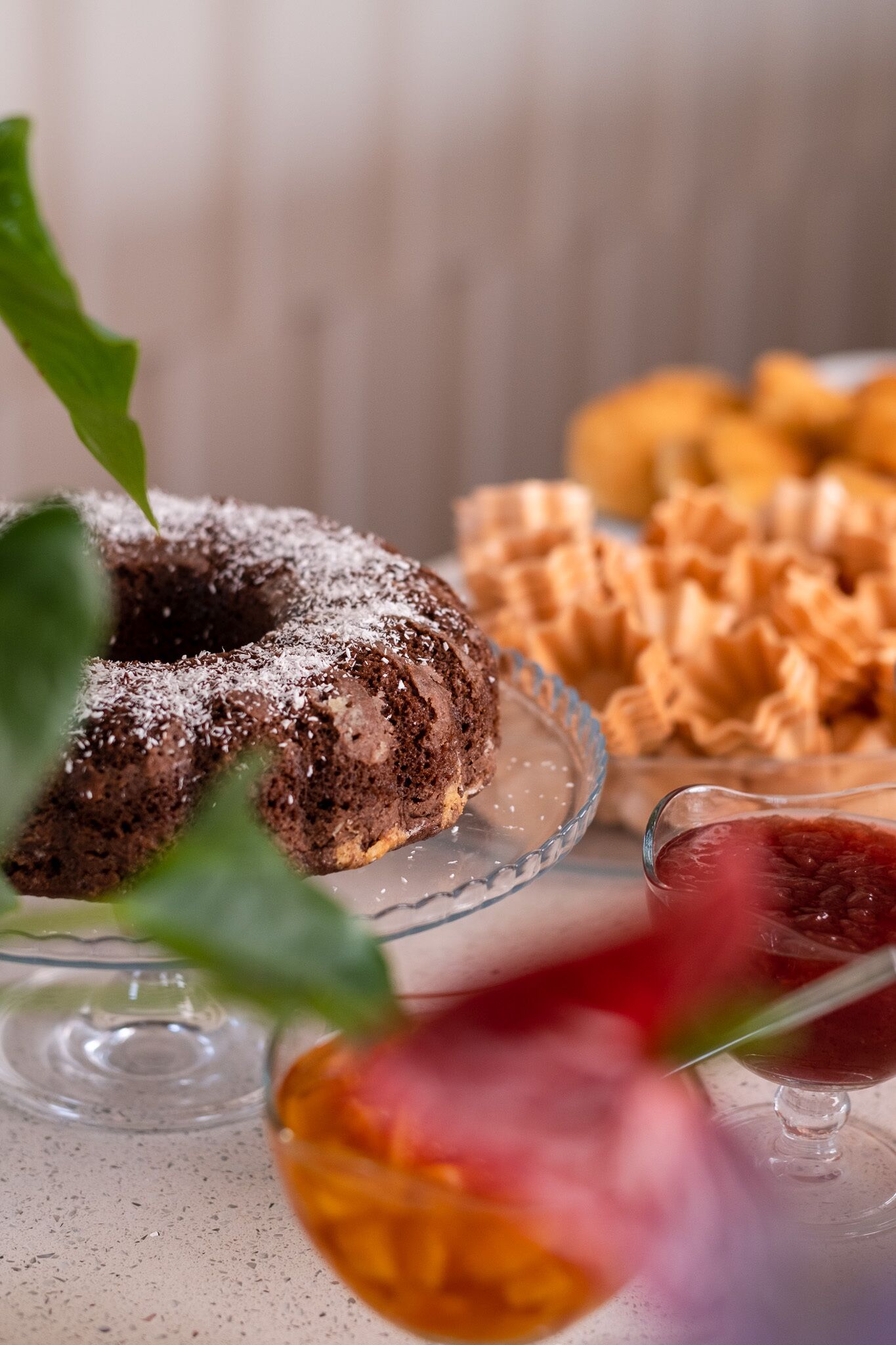 A dessert table with a chocolate bundt cake, waffles, and a glass of red drink.