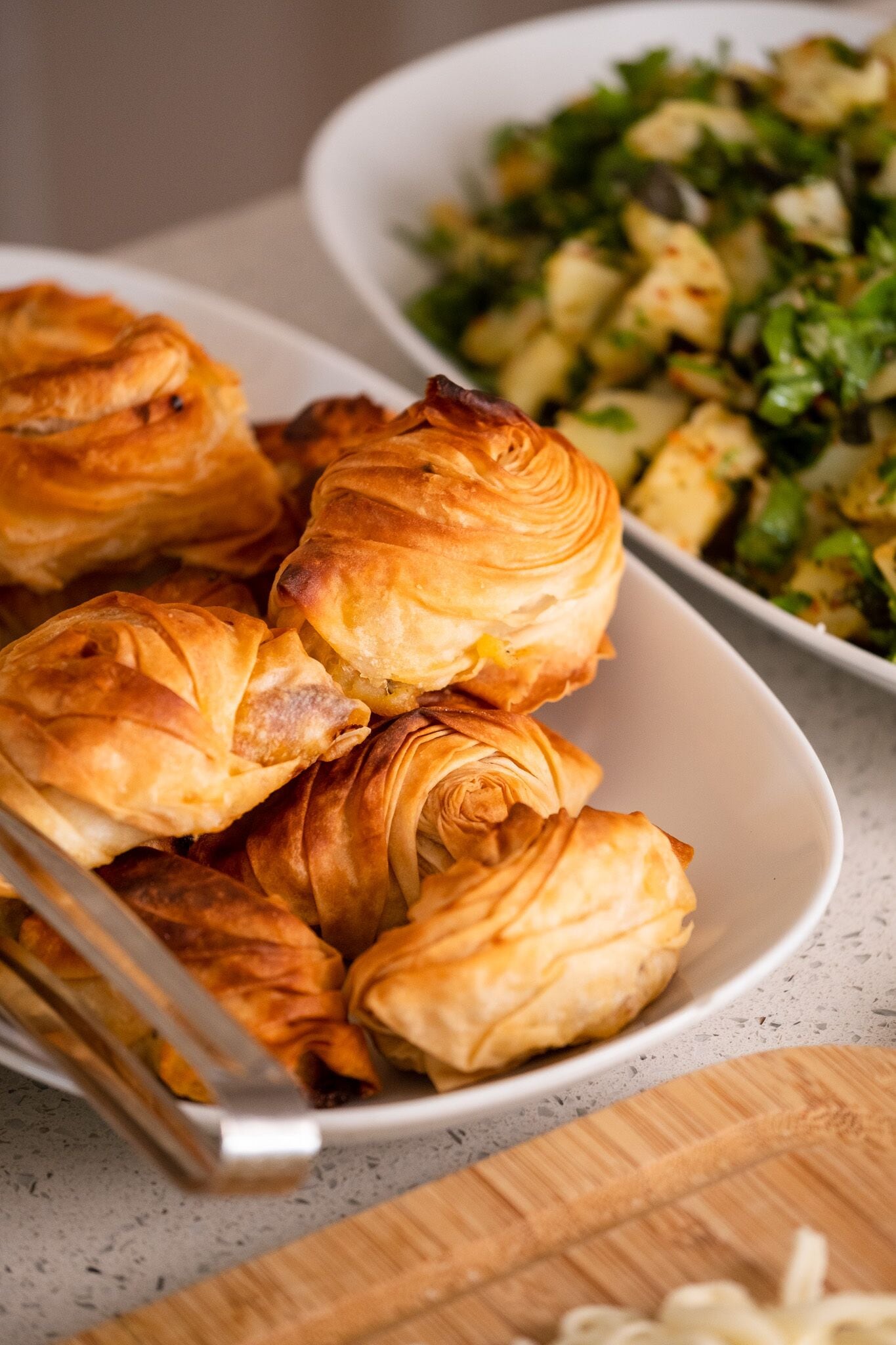A bowl of pastries and a side dish of vegetables.