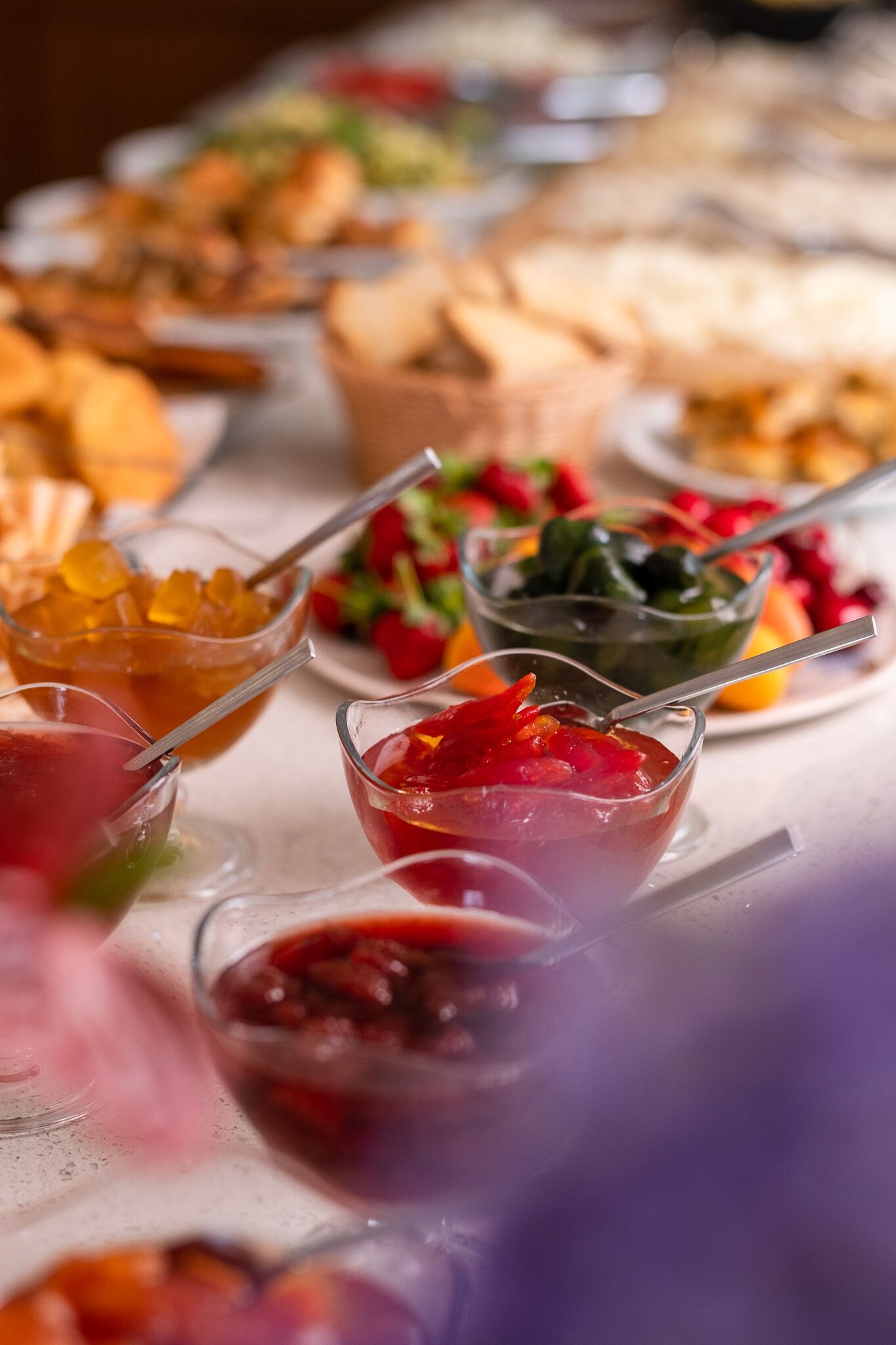 A table with various food items and drinks, including bowls of fruit, a plate of bread, and a glass of red beverage.