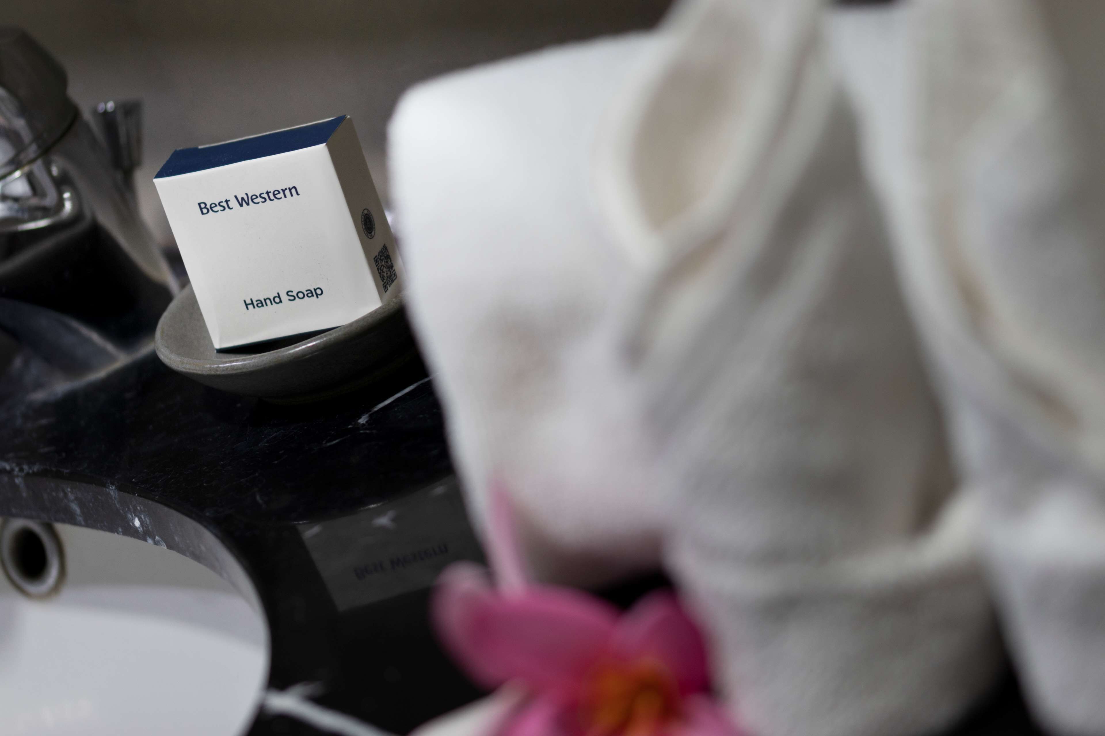 A hand soap dispenser labeled "Best Western Hand Soap" on a black countertop.