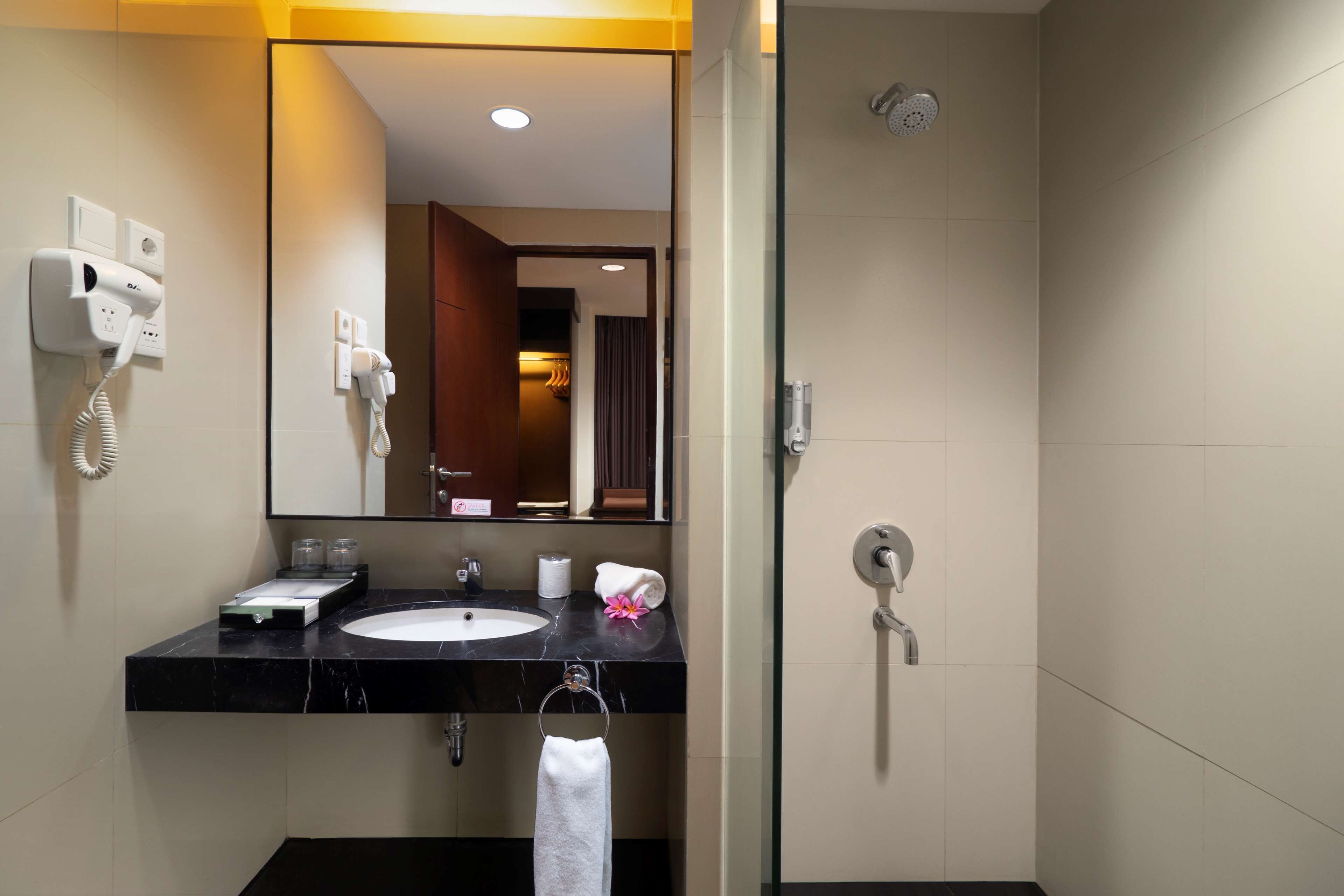 A modern bathroom with a black marble sink, a mirror, a towel rack, and a shower.