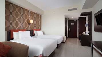A hotel room with two beds, a TV, a desk, and a bathroom visible through an open door.