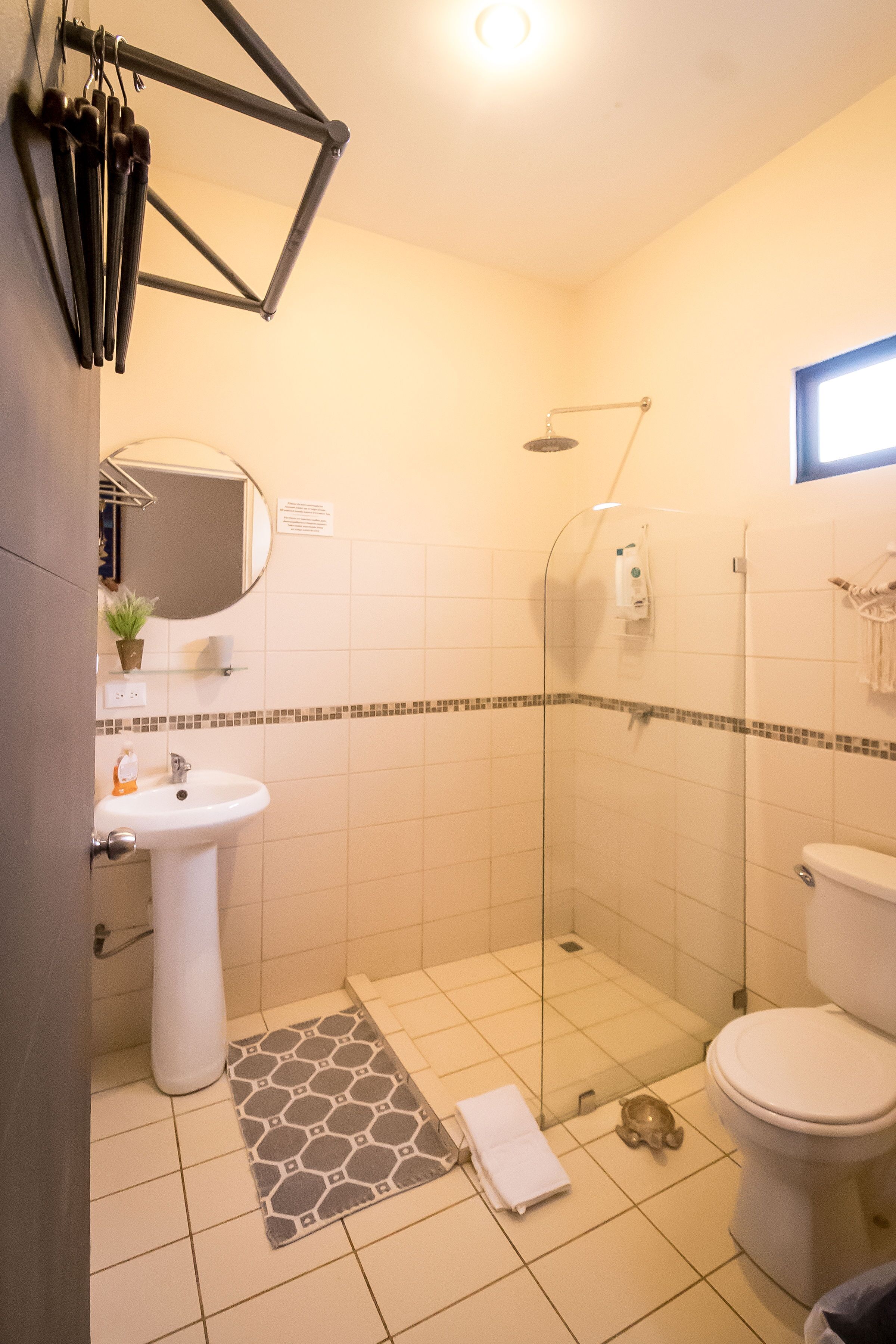 A bathroom with a sink, toilet, shower, and a mirror.