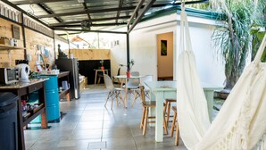 A kitchen with a coffee machine, a refrigerator, and a blue barrel. There are chairs and a table in the dining area. - Terida Airport B&B (Desamparados)