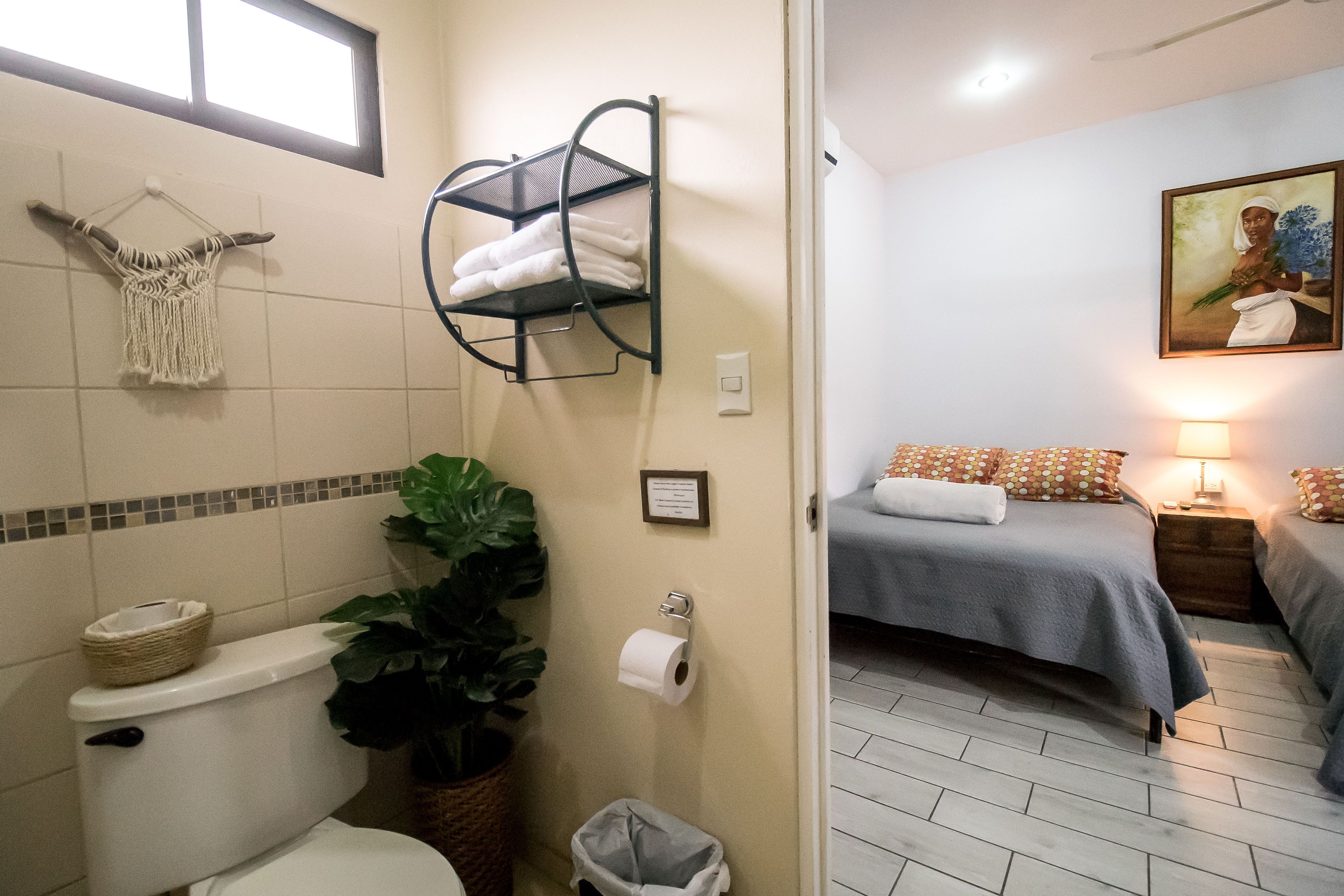 A bathroom with a toilet, a sink, a towel rack, and a trash bin.
