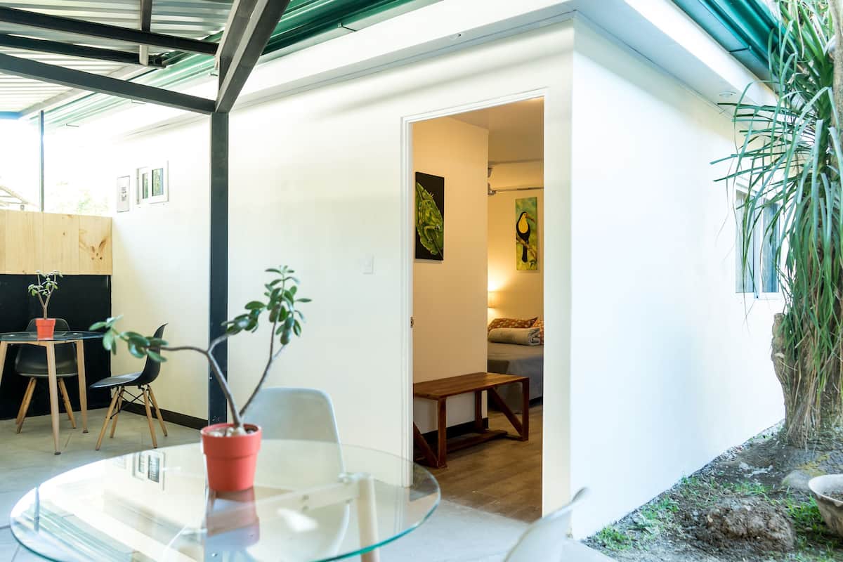 Een modern interieur met een glazen tafel, een potplant en een houten bank.