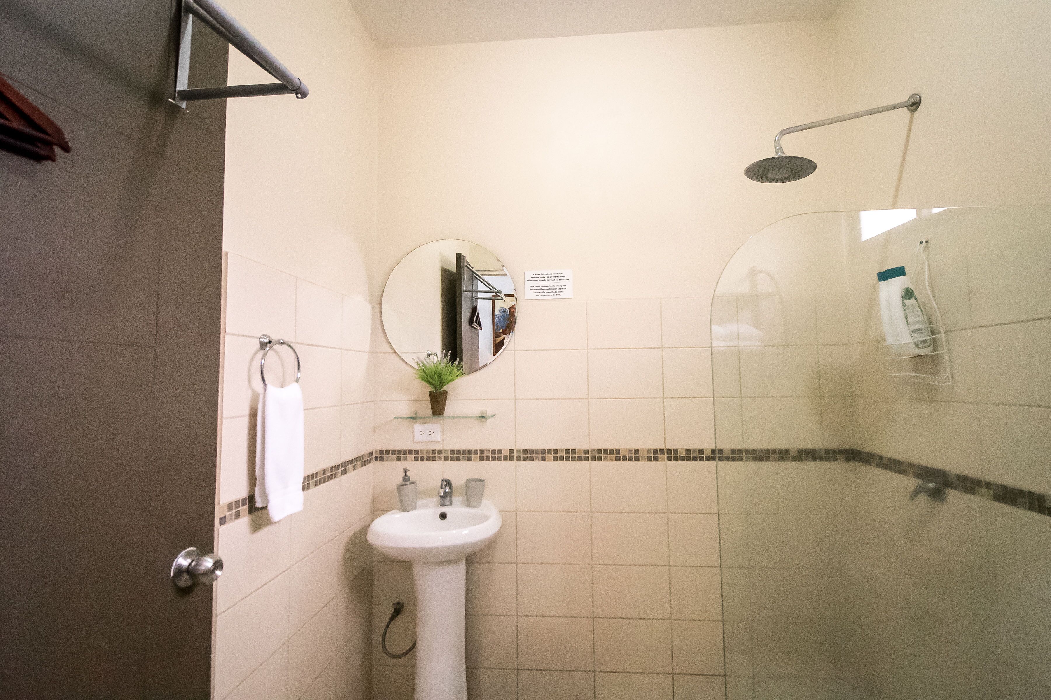 A bathroom with a sink, mirror, and shower.