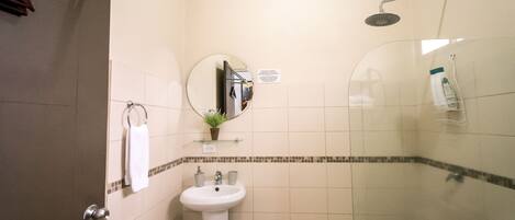A bathroom with a sink, mirror, and shower.