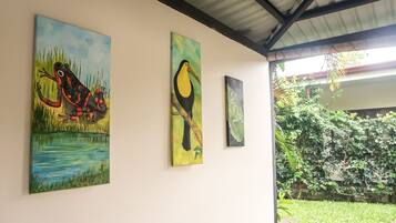 Three paintings on a wall, depicting a frog, a toucan, and a bird.