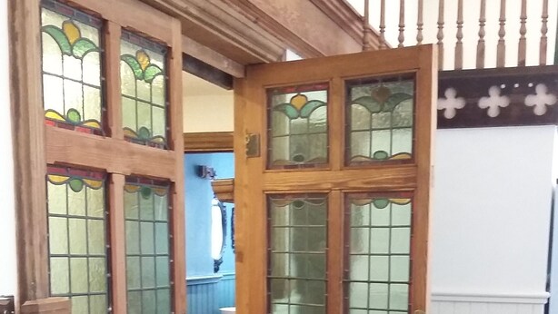 Une porte en bois ornée de panneaux de vitrail et un portail en métal.