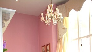 Une chambre à coucher avec un lit, une chaise, un lustre et une fenêtre avec des rideaux.