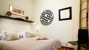 Une chambre bien rangée, avec un lit, une table de chevet, une lampe et une chaise.