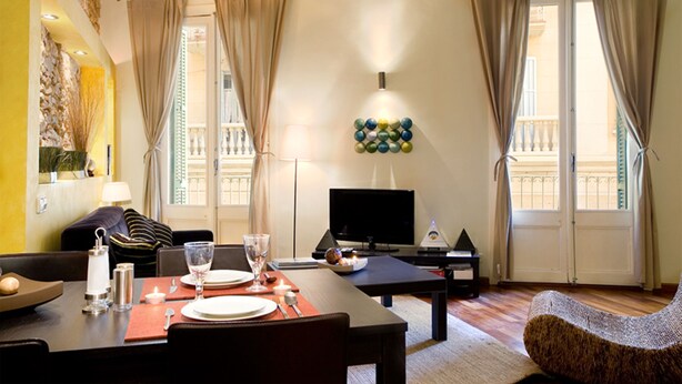 Un salon moderne comprenant un coin repas, un téléviseur à écran plat et une œuvre d’art décorative au mur.