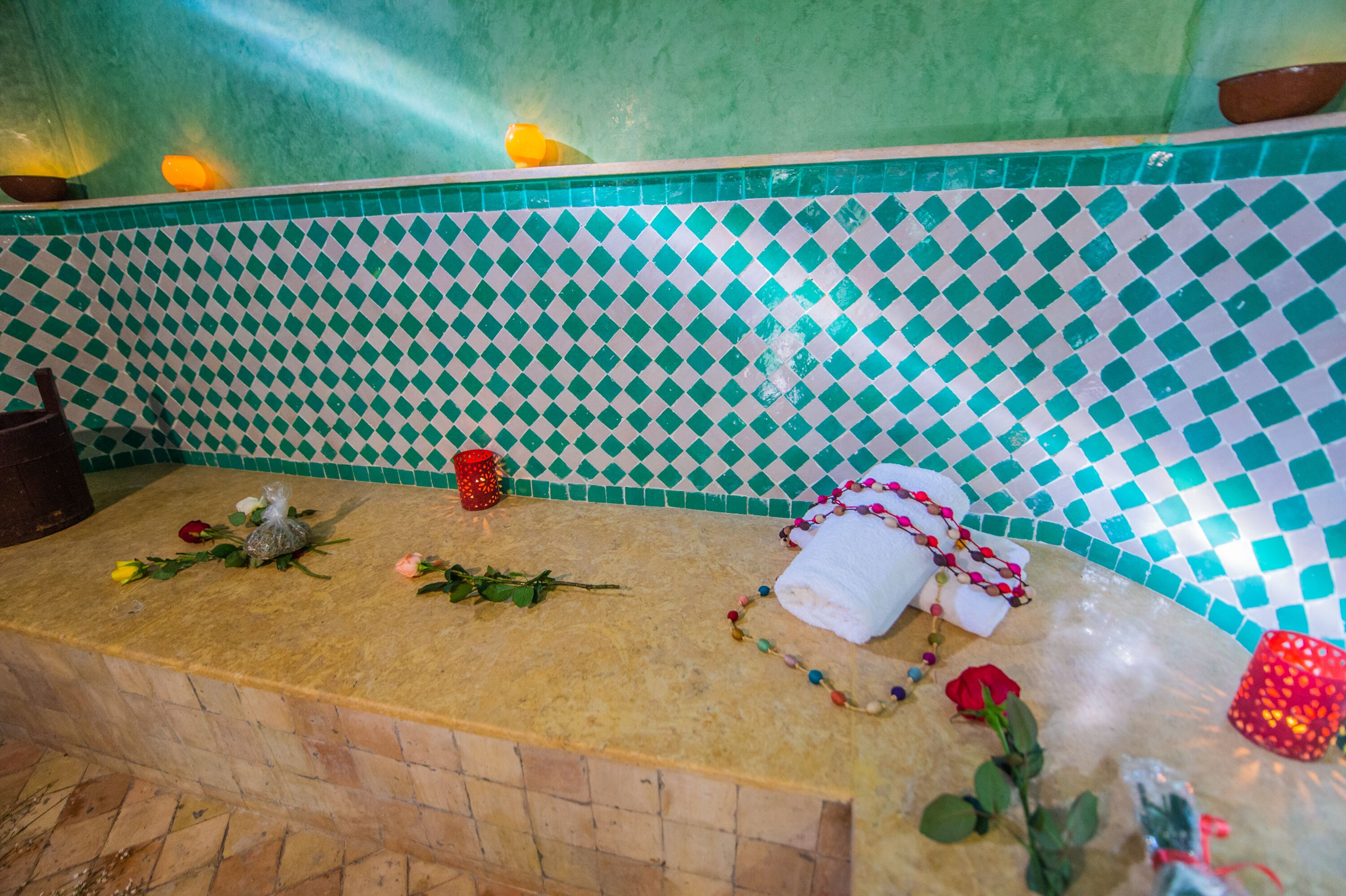 Une salle de bain avec un mur recouvert de carreaux à motifs géométriques, un plan de toilette en pierre et un porte-serviettes.