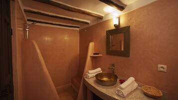 A bathroom with a bathtub, a sink with a large bowl, a towel, and a mirror on the wall.