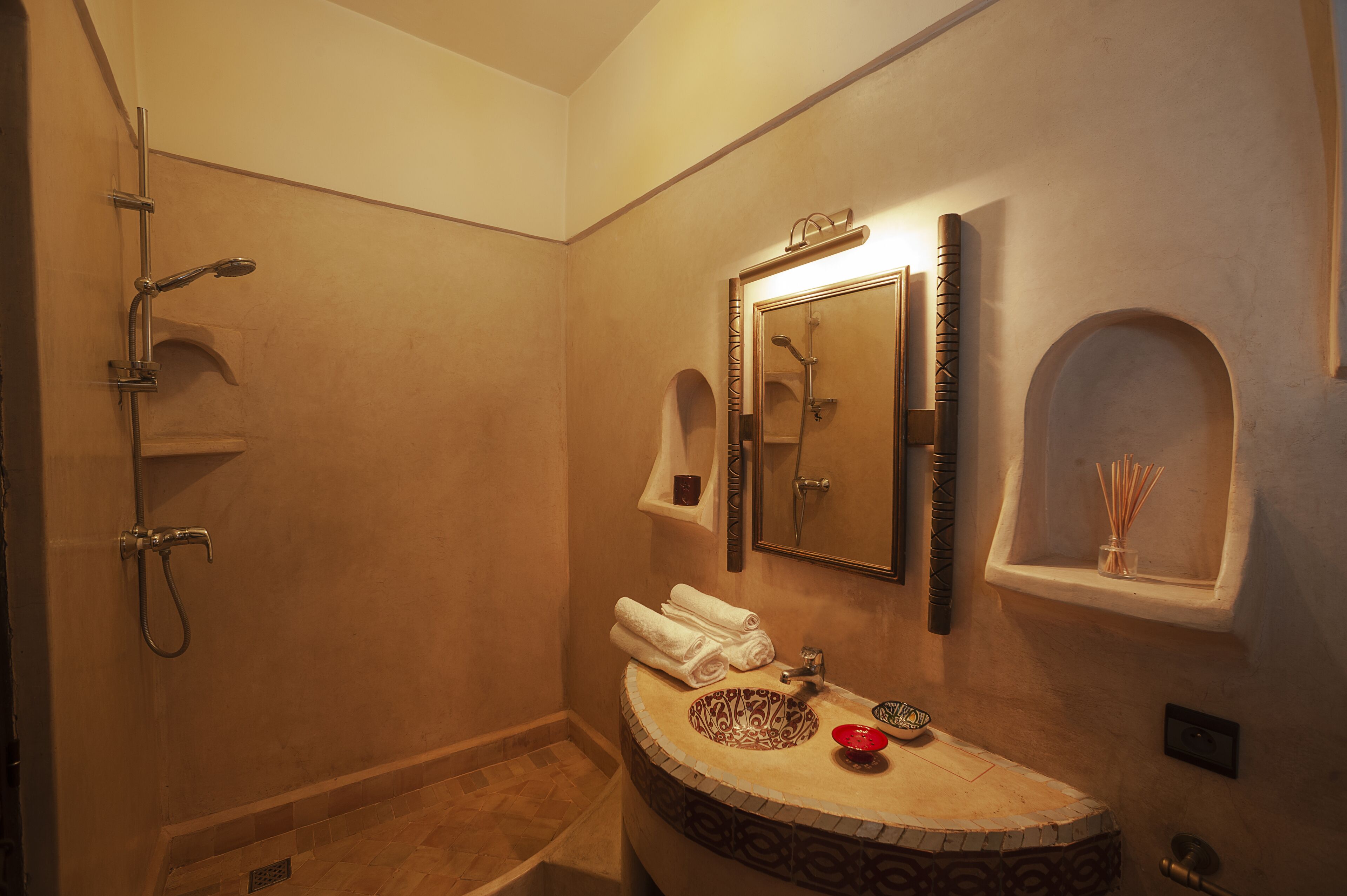 Un baño con ducha, lavabo de diseño y espejo con repisa superior.