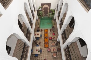 A rooftop pool area with a central pool, surrounded by seating and potted plants.