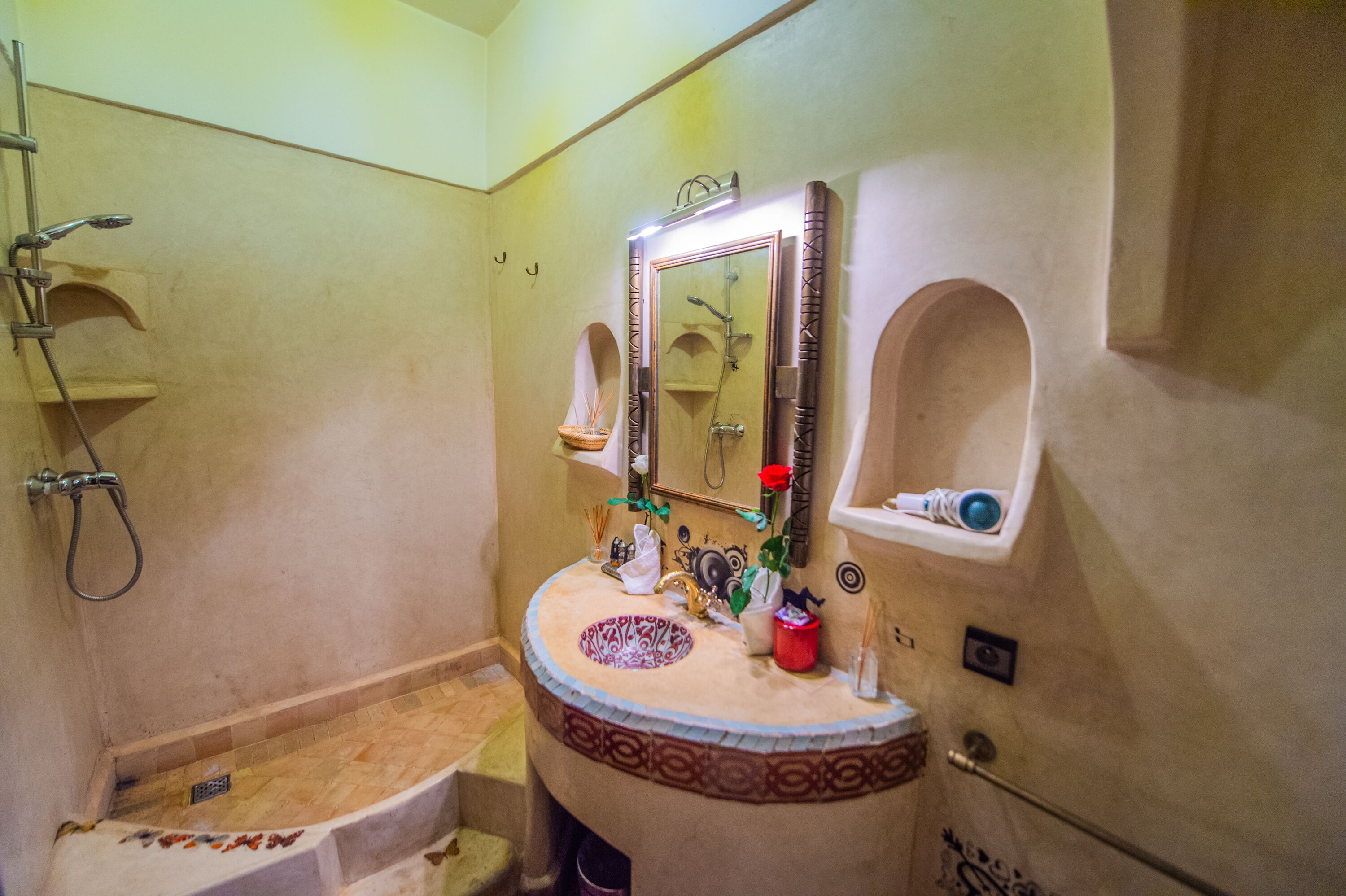 A bathroom with a sink, mirror, shower, and towel rack.