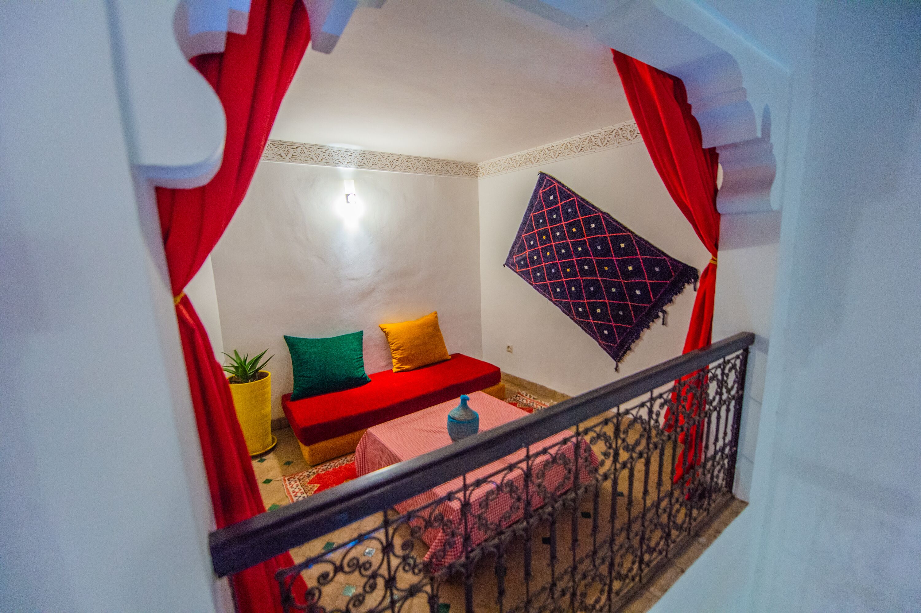 A room with a red sofa, a small table, and a potted plant.