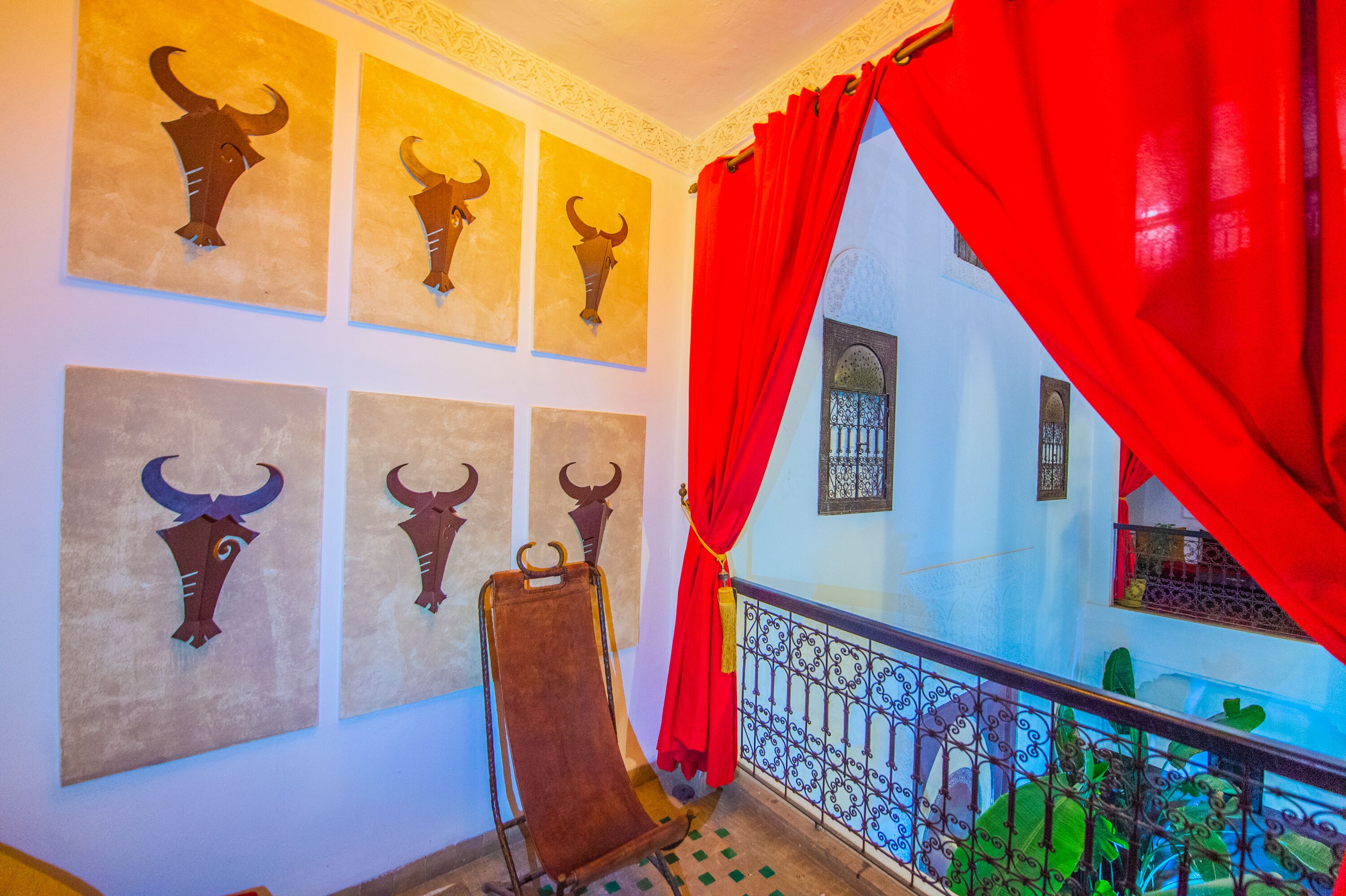 A room with bull horn decorations on the wall, a red curtain, and a balcony with a wrought iron railing.