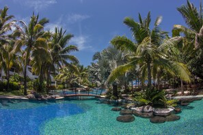 Piscina de un resort rodeada de palmeras y rocas.