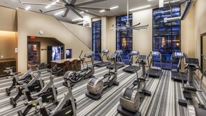 Un gimnasio de hotel con cintas de correr, bicicletas estáticas y un espejo grande.