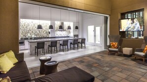 Un interior moderno con una zona de bar, asientos y un televisor.