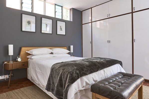 A bedroom with a bed, bedside table, lamp, and a wardrobe.