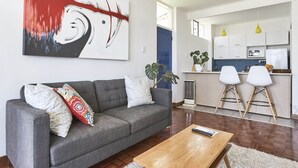 A modern living room with a grey sofa, a coffee table, and a painting on the wall. - House Sandrock Muckleneuk (Pretoria)