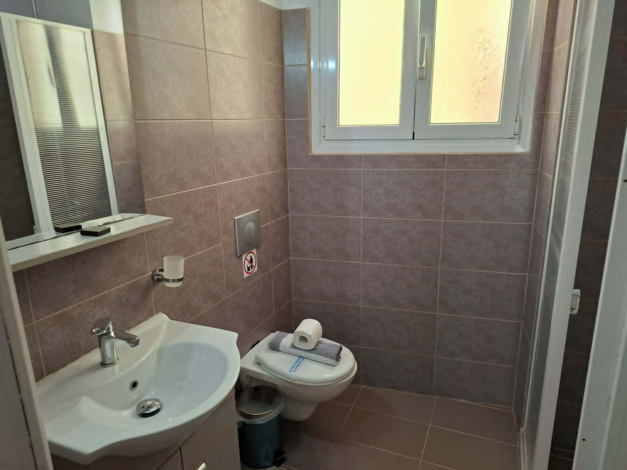 Un baño con lavamanos, inodoro y ventana.