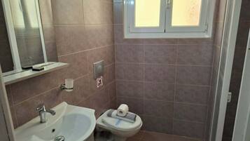 Un baño con lavamanos, inodoro y ventana.