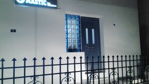 A building with a metal fence, a door, and a window with a grid pattern. - Mastic Point Studios (Chios)