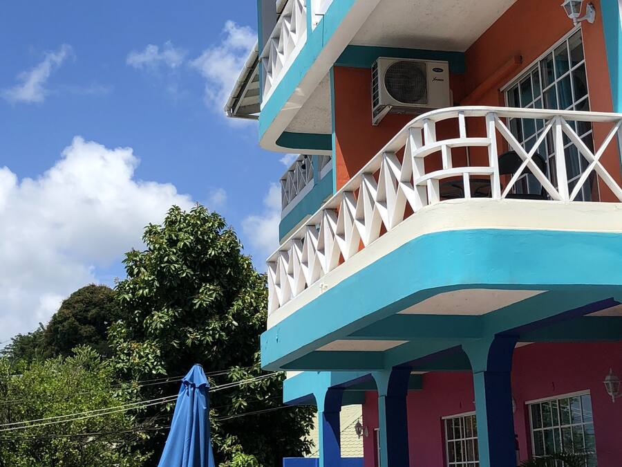 Un edificio de varios pisos con balcones, unidades de aire acondicionado y un paraguas azul.