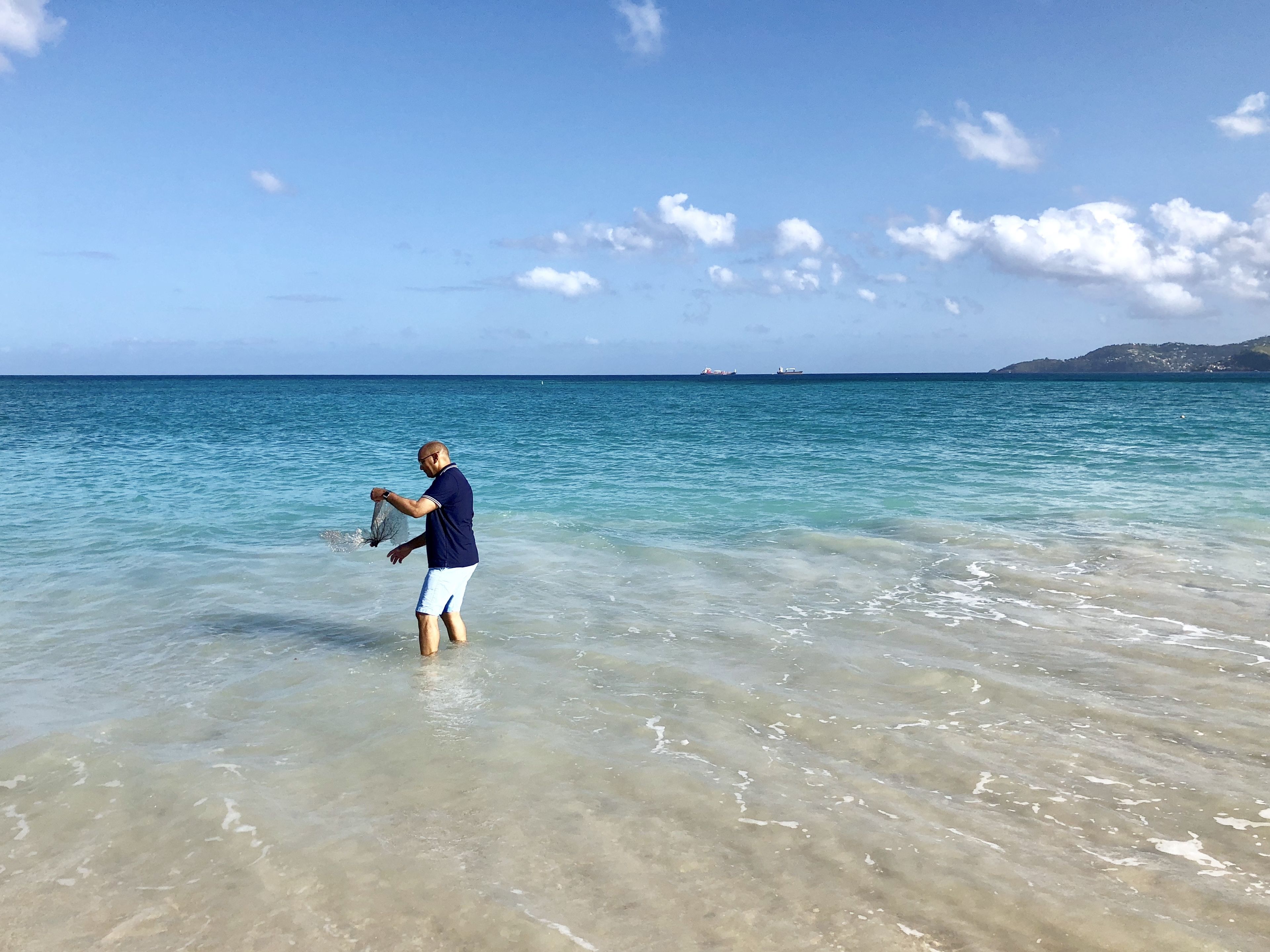 A man standing in shallow water, holding a net.