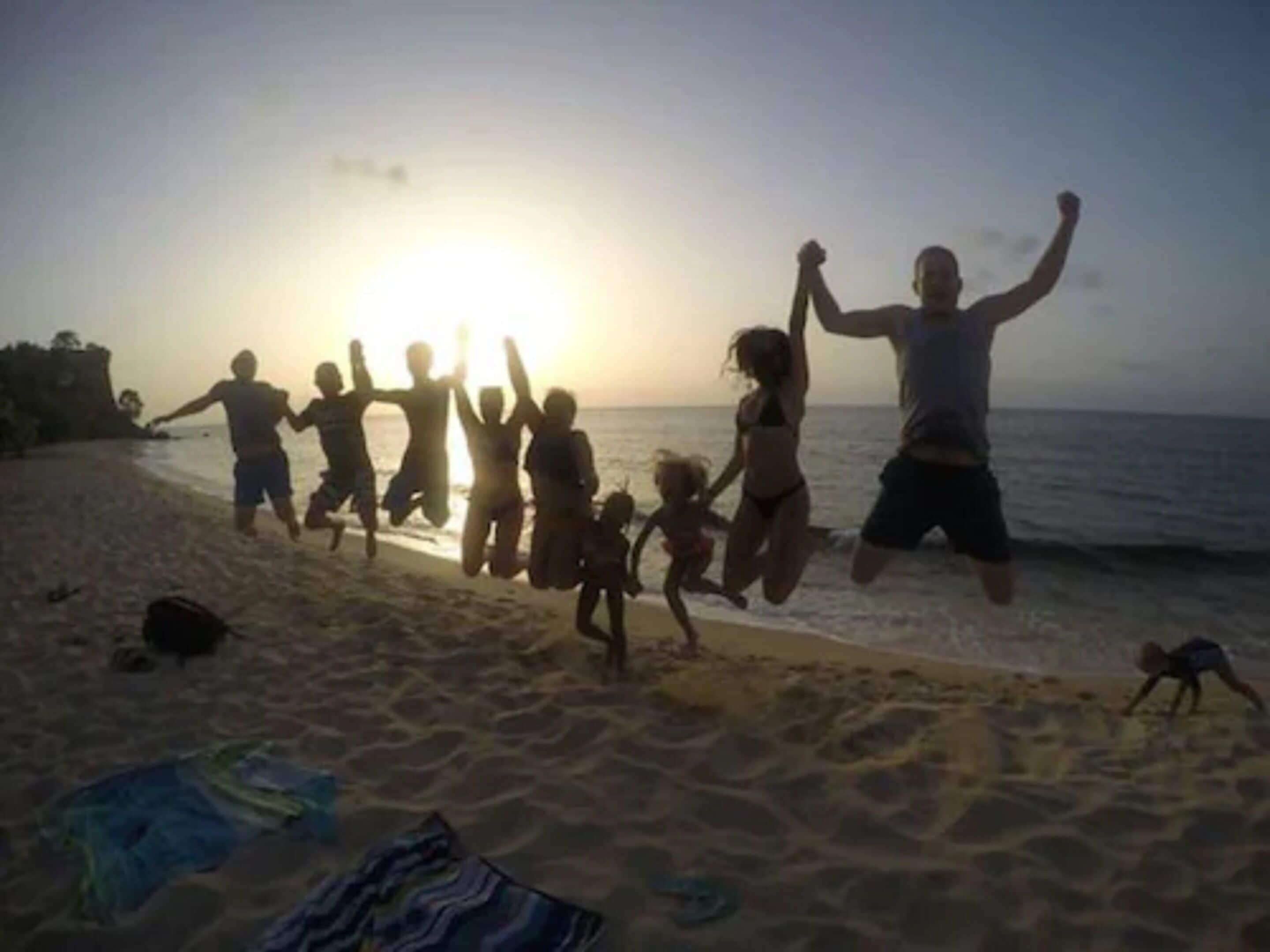 A beach scene with people jumping and playing in the sand.