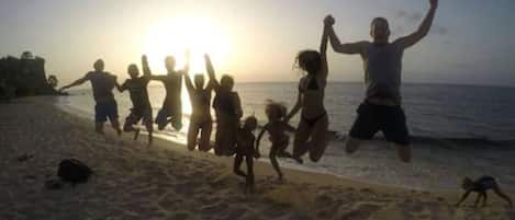 A beach scene with people jumping and playing in the sand.