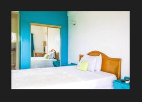 Una habitación de hotel con una cama grande, un cabecero de madera y una mesita de noche con un control remoto.