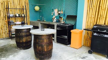 An outdoor kitchen area with a gas stove, a grill, and a table with two barrels.