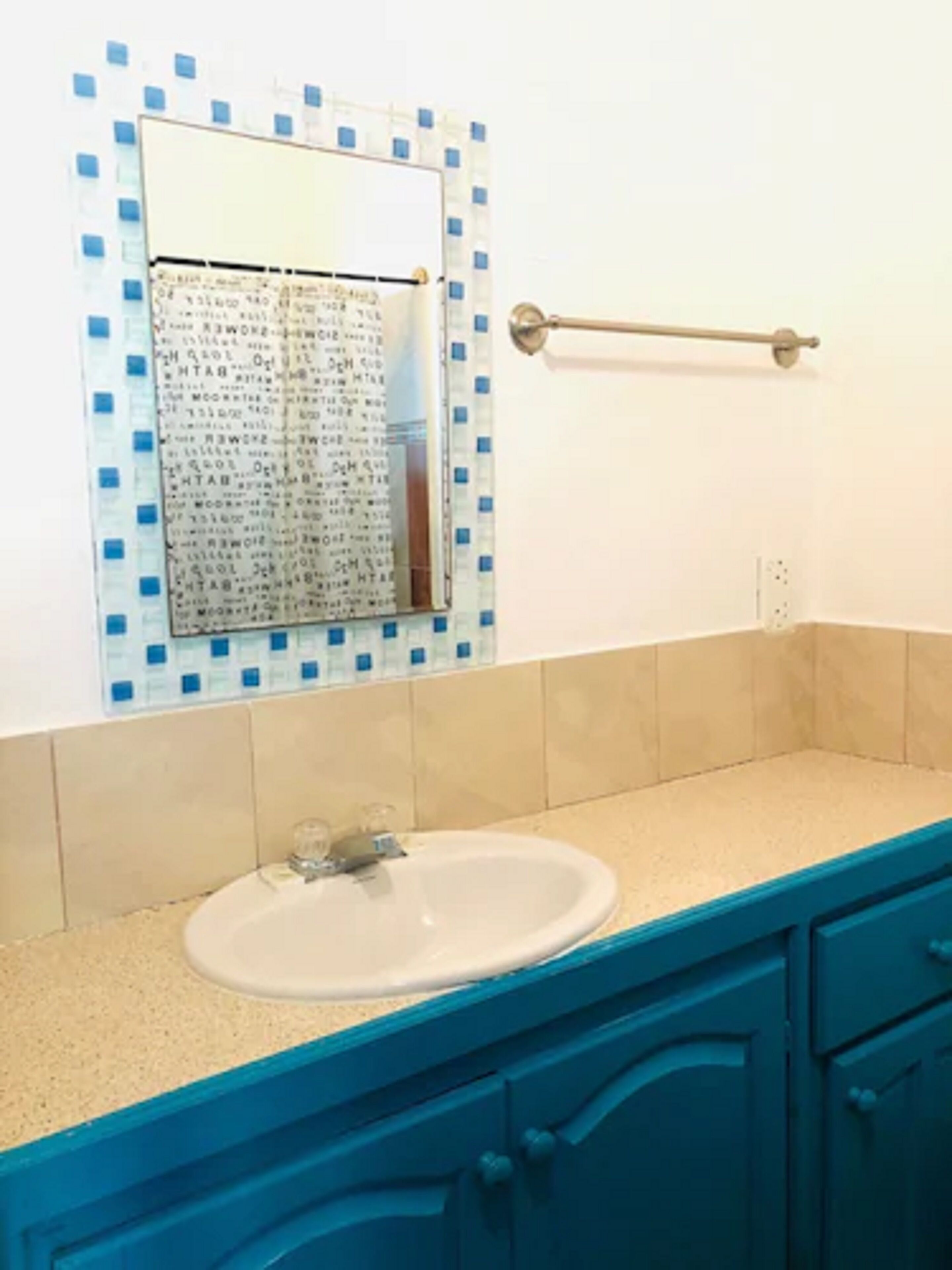 Casa de banho com lavatório, espelho e armários azuis.