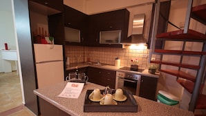 A modern kitchen with dark cabinetry, a granite countertop, and a stainless steel range hood. - Point Twins Apartments (Chios)