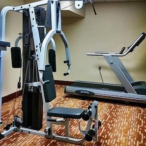 A gym with a treadmill and a multi-functional weight machine.