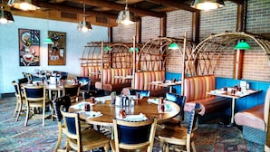 Un restaurante con mesas y cabinas de madera, asientos de cuero y lámparas verdes colgantes.
