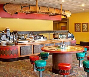 A restaurant with a buffet counter, colorful stools, and a patterned carpet.