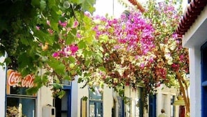 A narrow street with outdoor seating, a Coca-Cola sign, and a building with a dome. - Poseidon Beach Villas (Lavreotiki)