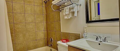 Un baño con bañera, inodoro, lavamanos y espejo.