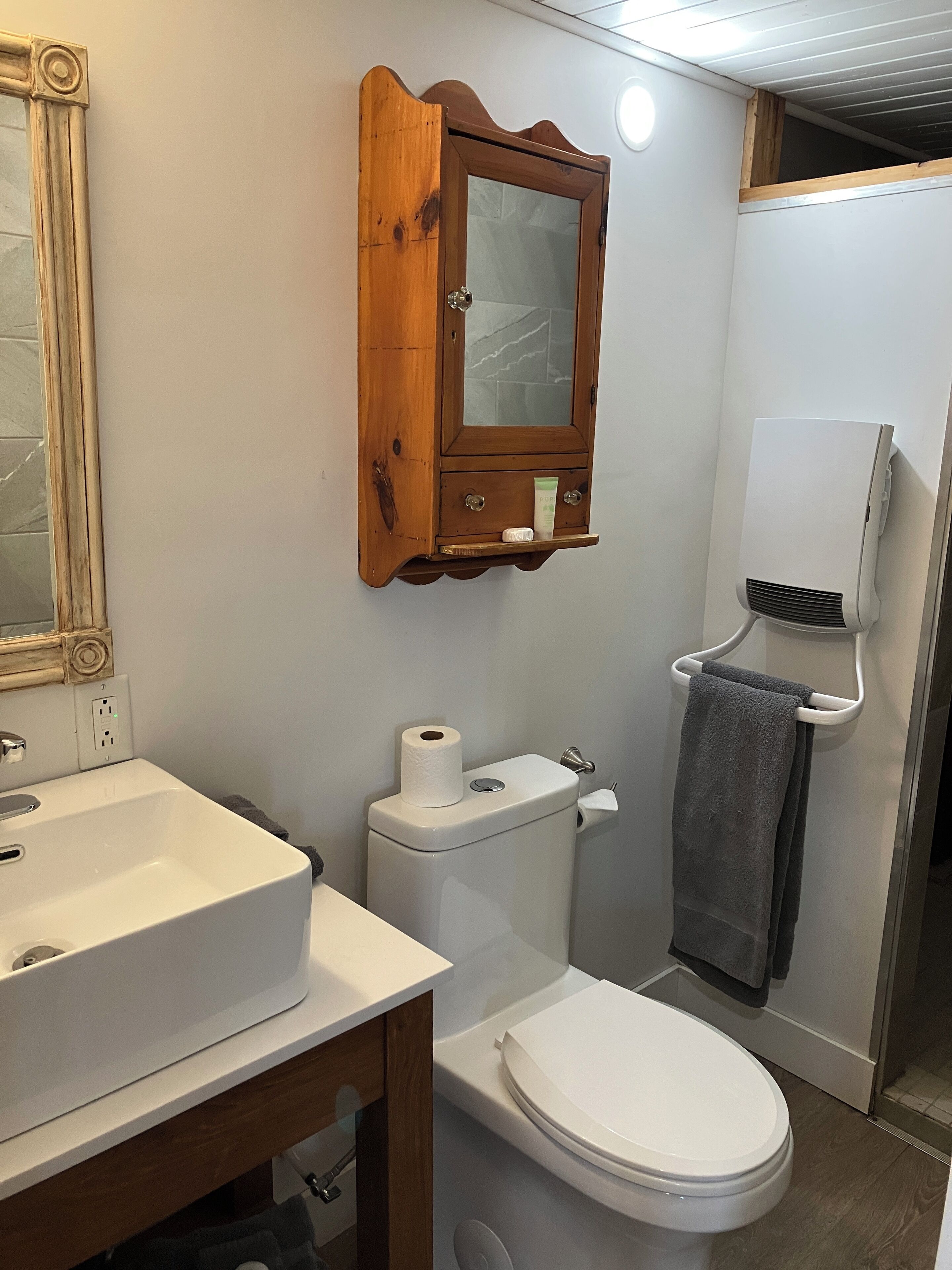 A bathroom with a white sink, toilet, and a wooden medicine cabinet with a mirror.