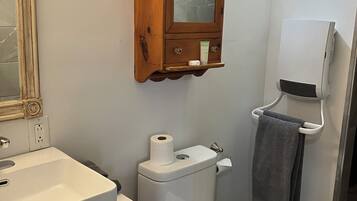 A bathroom with a white sink, toilet, and a wooden medicine cabinet with a mirror.