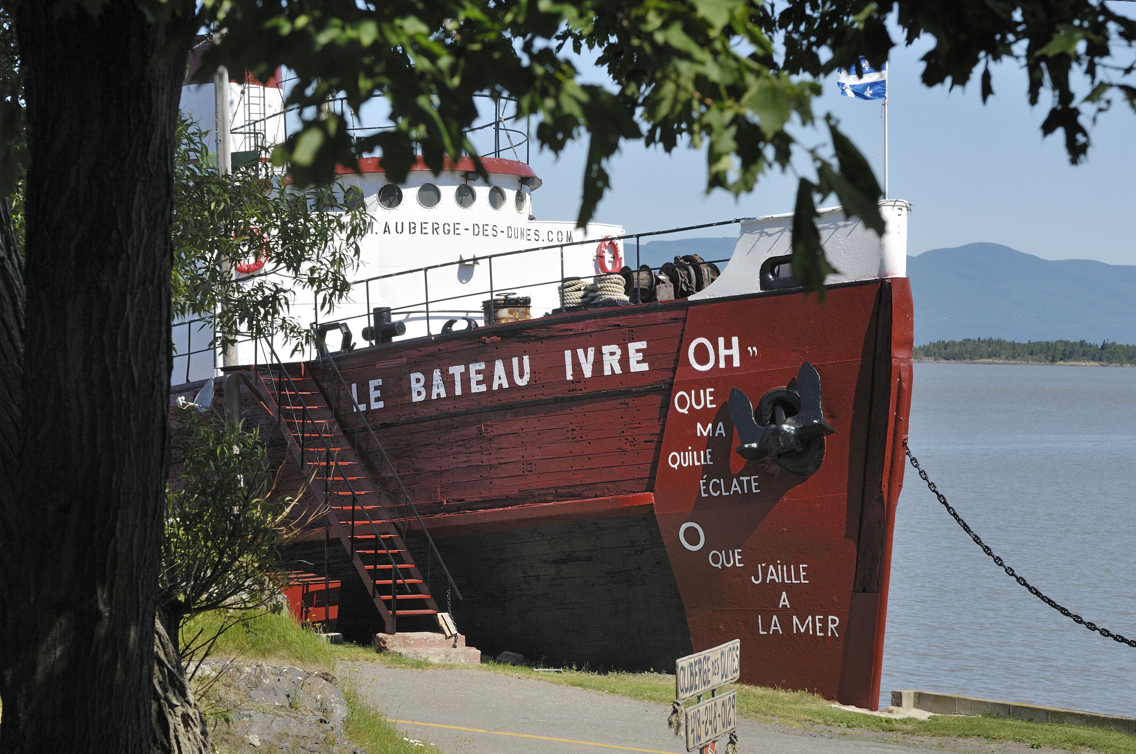 A large ship named "Le Bateau IVRE OH" docked at a port with a staircase leading up to its deck.