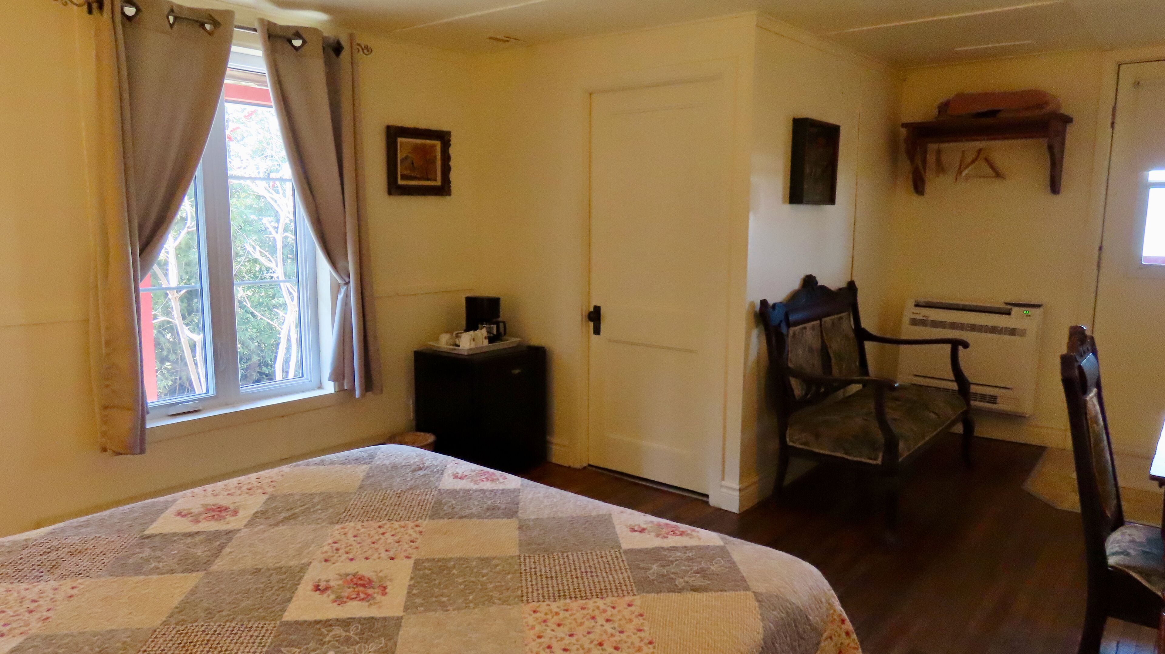 A bedroom with a bed, a chair, a desk, and a radiator.