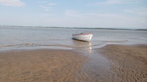 A boat on a sandy beach with water. - Auberge Pourvoirie Isle-aux-Grues (Saint-Antoine-de-l'Isle-aux-Grues)